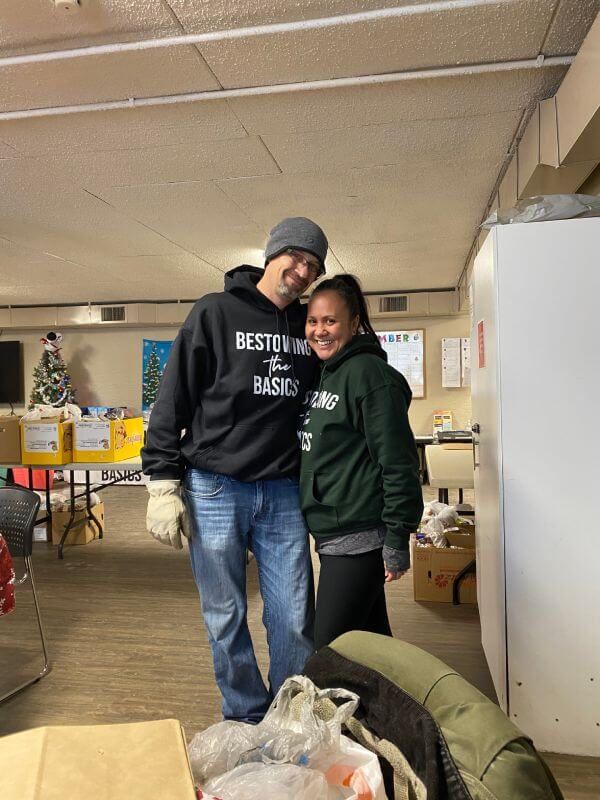 Two Bestowing the Basics volunteers in branded hoodies at a holiday distribution