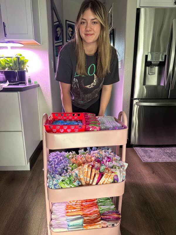 A volunteer with a three-tier cart stocked with period supplies for a school restroom