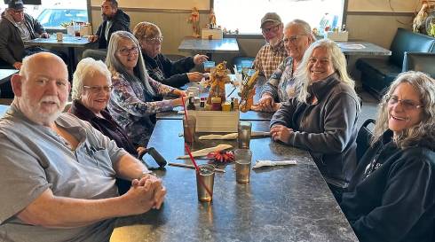 Neighbors sharing a free community meal around a table at The Country Boy Cafe